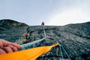 Menschen klettern an einem Seil eine Bergwand hoch